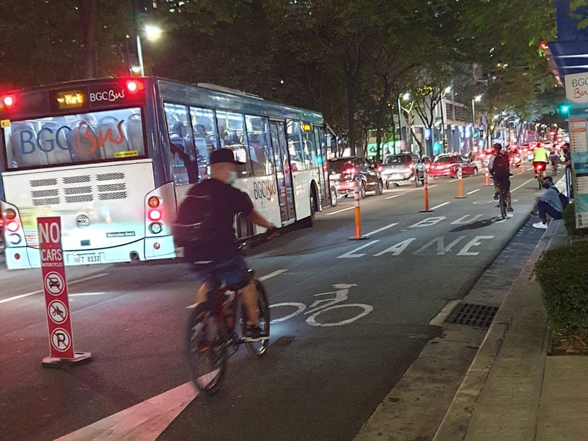 Cyclists ride safely along a protected bike lane separated from car traffic.